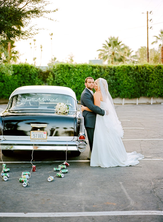 bride and groom pose near 1957 chevy bel-aire with cans on strings l'horizon wedding