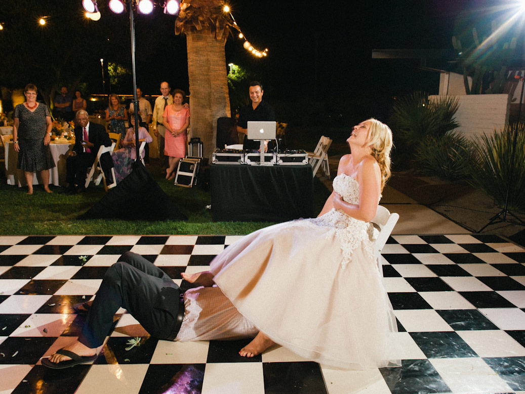 groom goes under bride's dress to retrieve garter on checkerboard dancefloor at l'horizon palm springs wedding reception