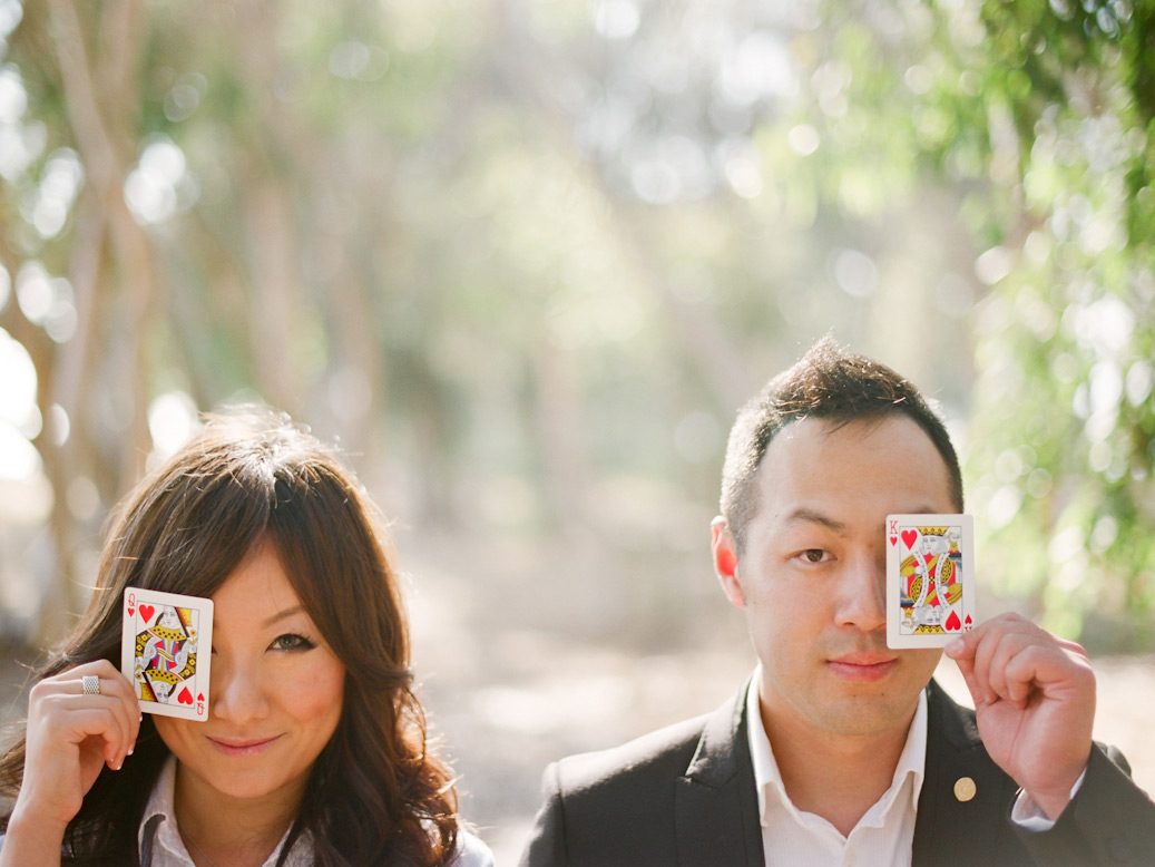 couple hold playing cards over eyes during la jolla elopement photo shoot