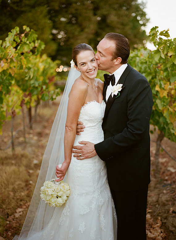 groom kissing bride in vineyard andretti winery wedding