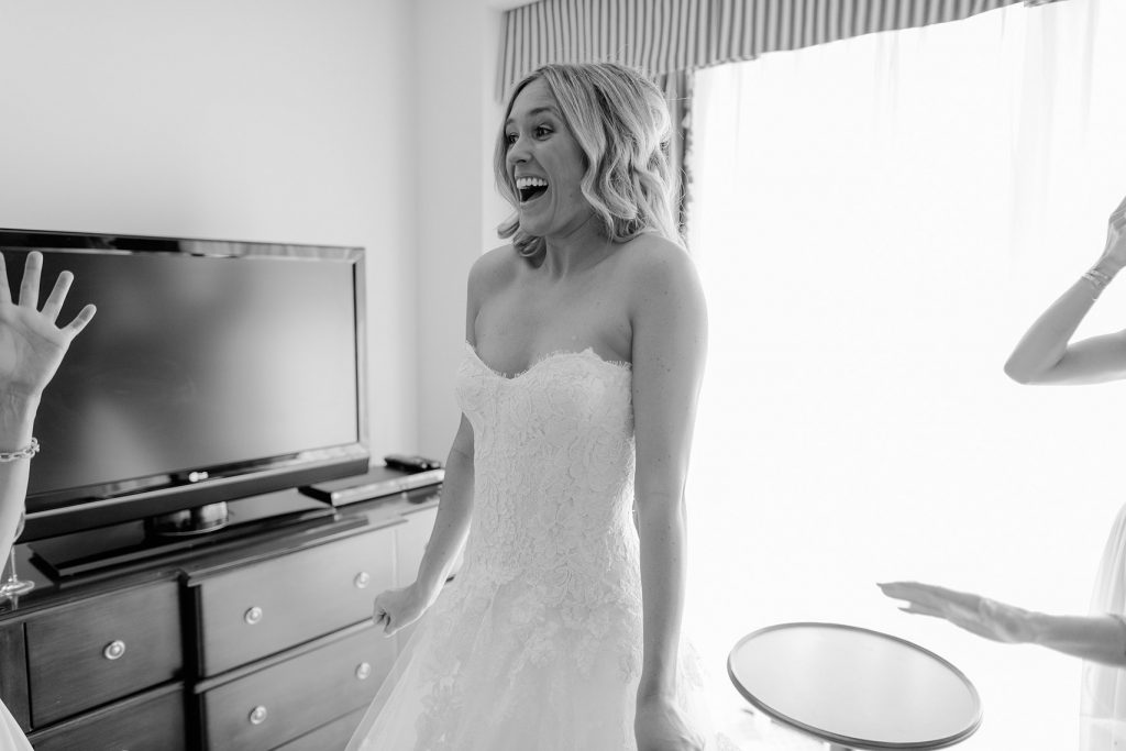 bride screaming with excitement as she puts on her wedding gown