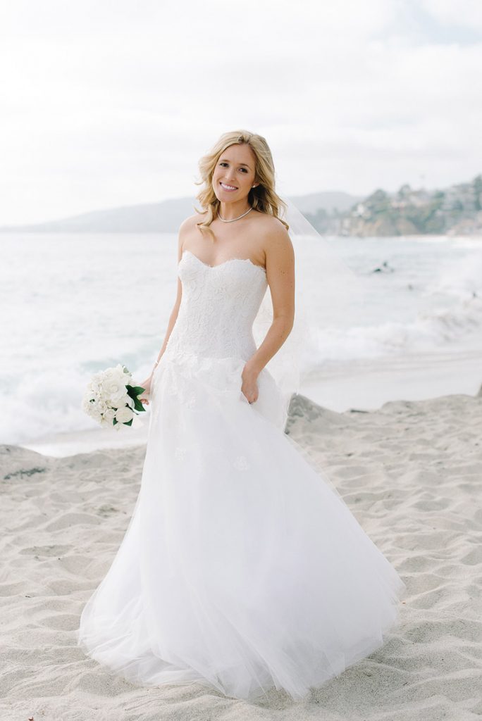 bride wearing monique lhuillier gown posing on beach montage laguna beach wedding