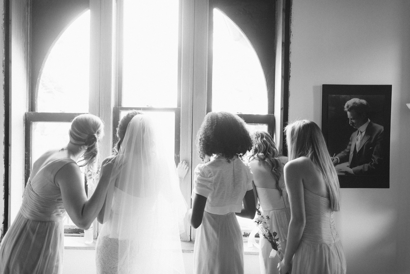 bride and bridesmaids watch guests arrive through window before National Museum of Puerto Rican Arts & Culture chicago wedding photos