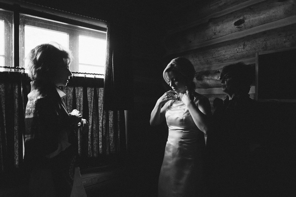 bride adjusts vintage wedding gown as mother and friend help before sun valley destination wedding at idaho rocky mountain ranch