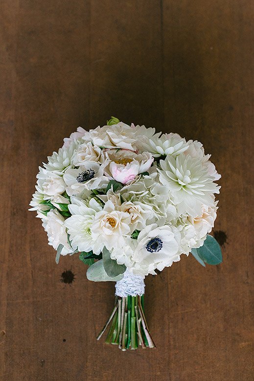 white bridal bouquet with mums and dahlias on wood floor