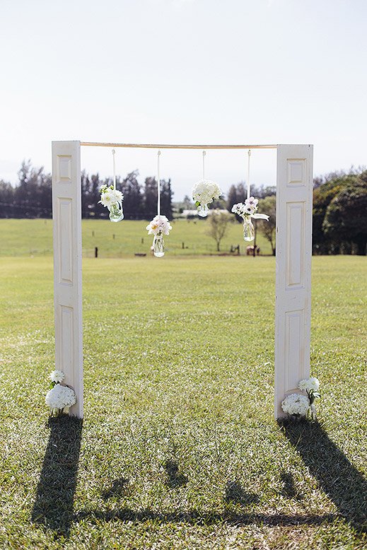 sunset ranch hawaii wedding arch made from door panels with white flowers hanging