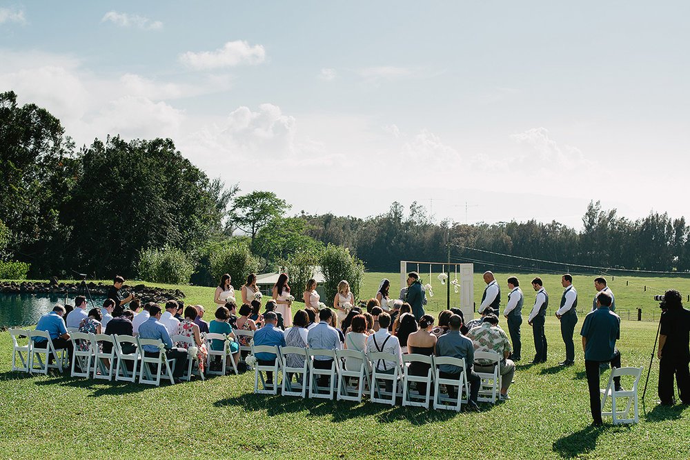 seated guests watch bride and groom exchange vows during sunset ranch hawaii wedding ceremony