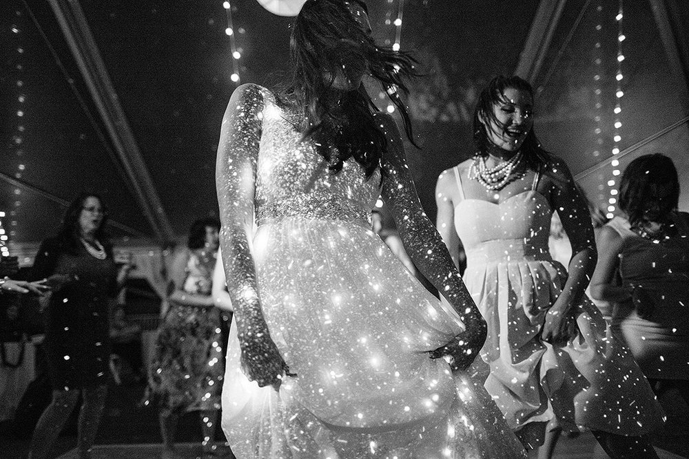 bride and guests dance under sparkling lights from dj booth