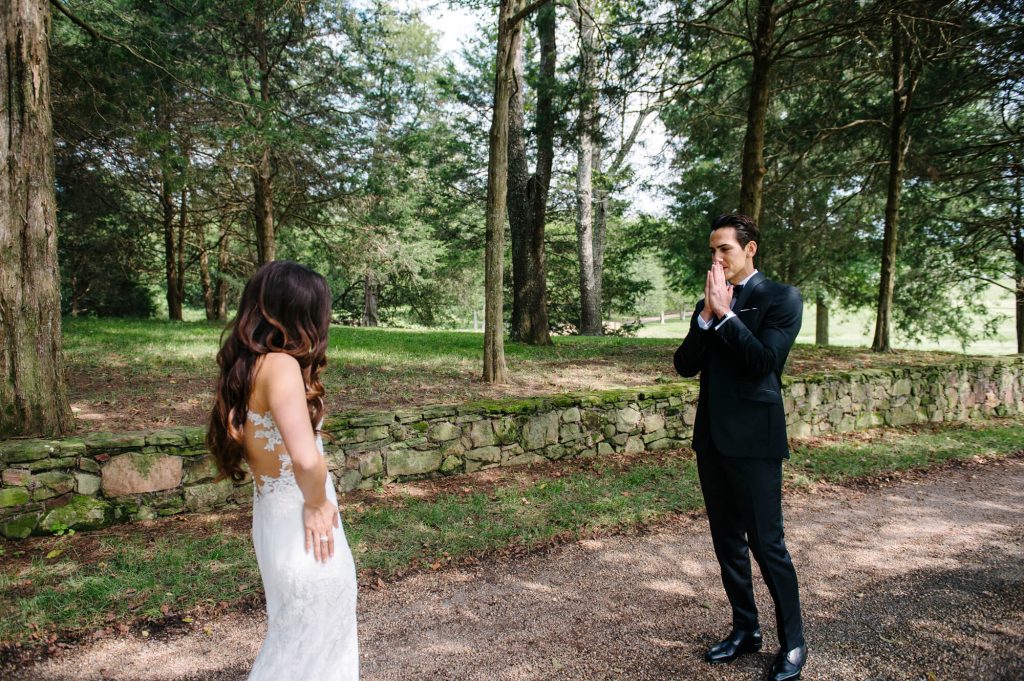 groom reacts to seeing bride first look woodsy path 