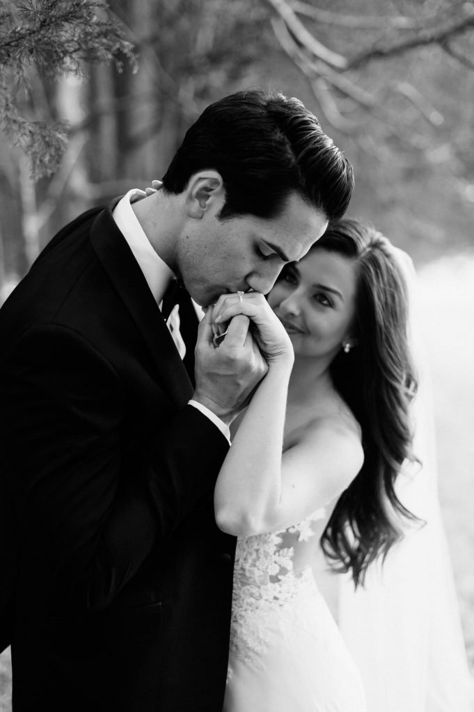 groom kisses brides hand black and white