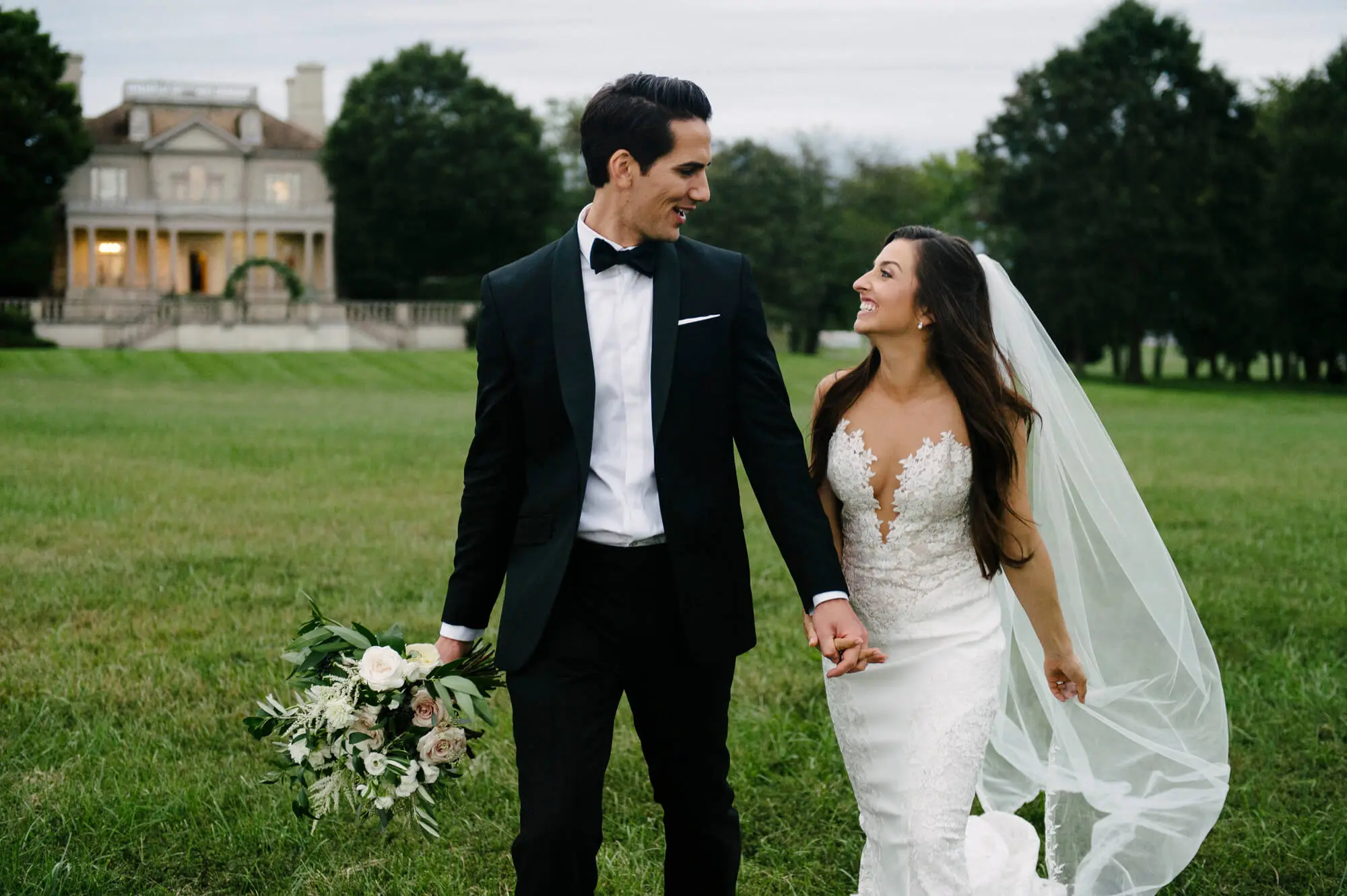 Husband and wife stroll the grounds of Great Marsh Estate after their classic destination wedding.