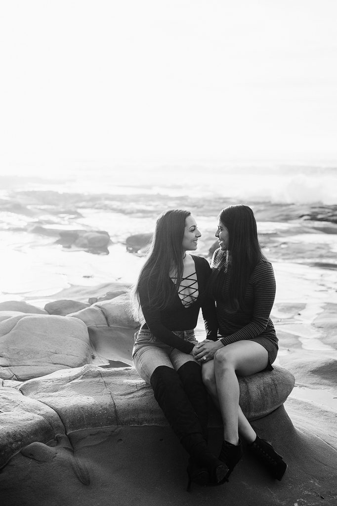 lesbian couple sit on rock same sex engagement photo