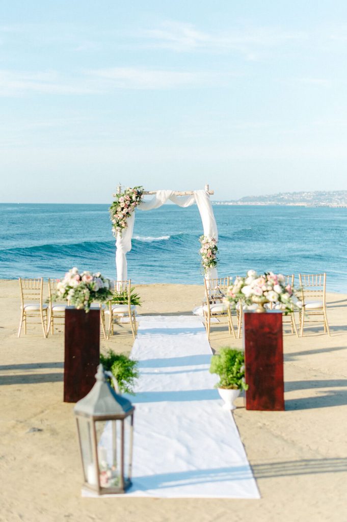 chiaviari chairs white runner colorful flowers driftwood arch sunset cliffs intimate wedding