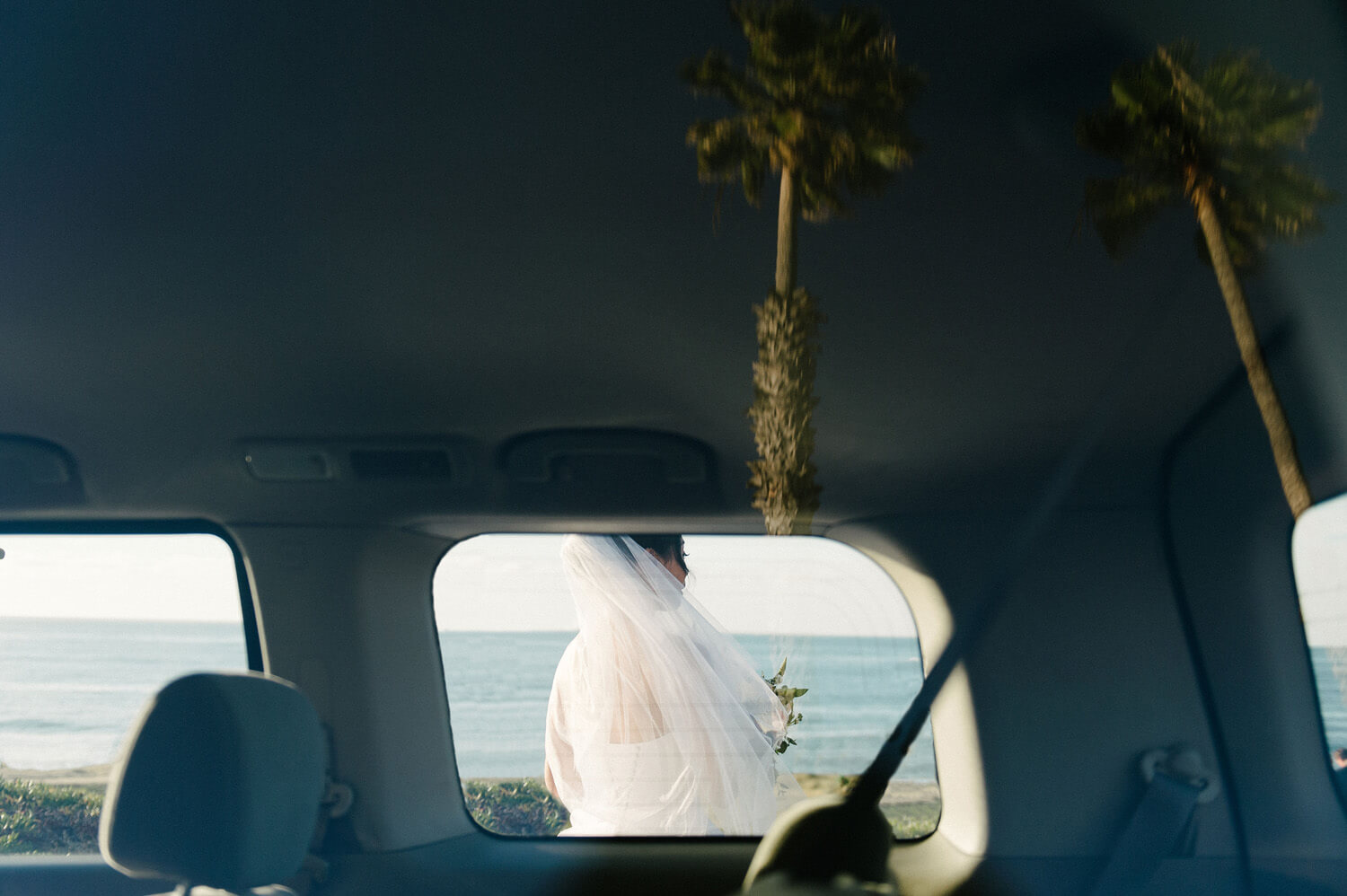 bride waits ocean car window palm trees reflection