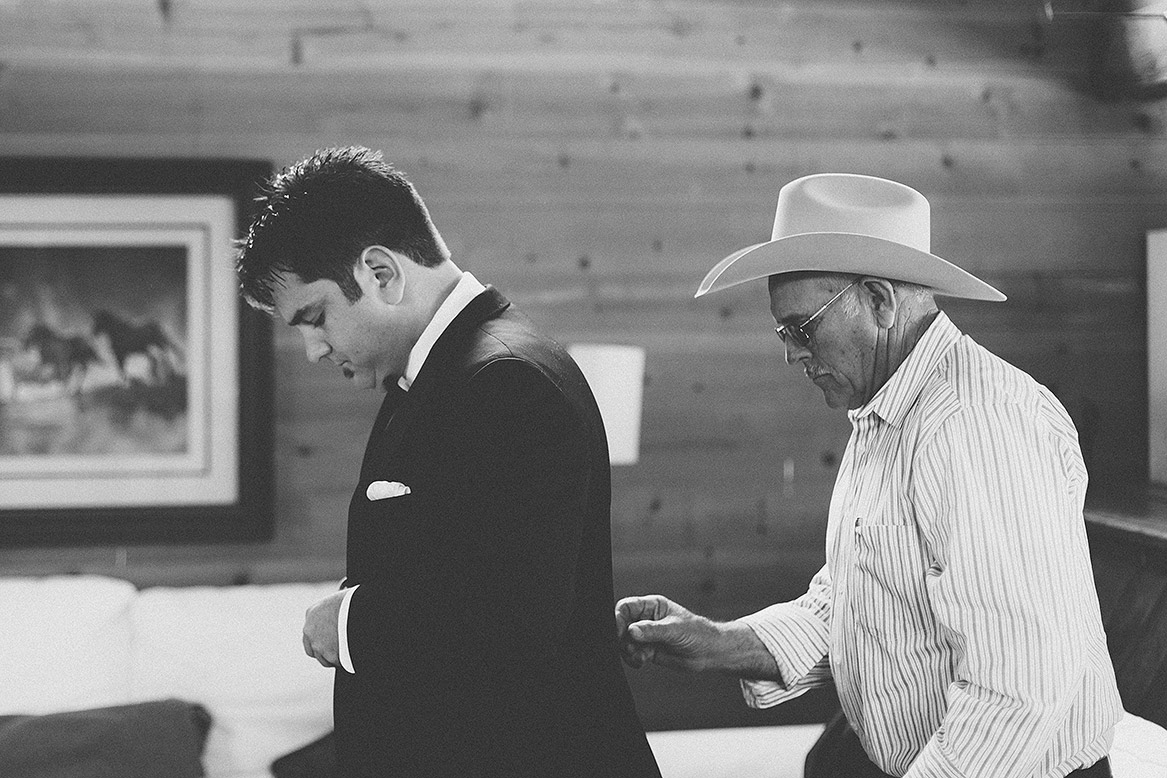 groom's father helps son with tuxedo jacket