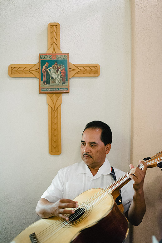 mariachi guitarist plays next to cross before catholic wedding ceremony