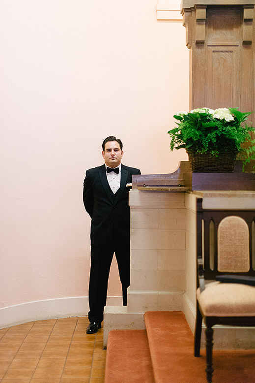 groom in tuxedo waits in church before catholic wedding ceremony