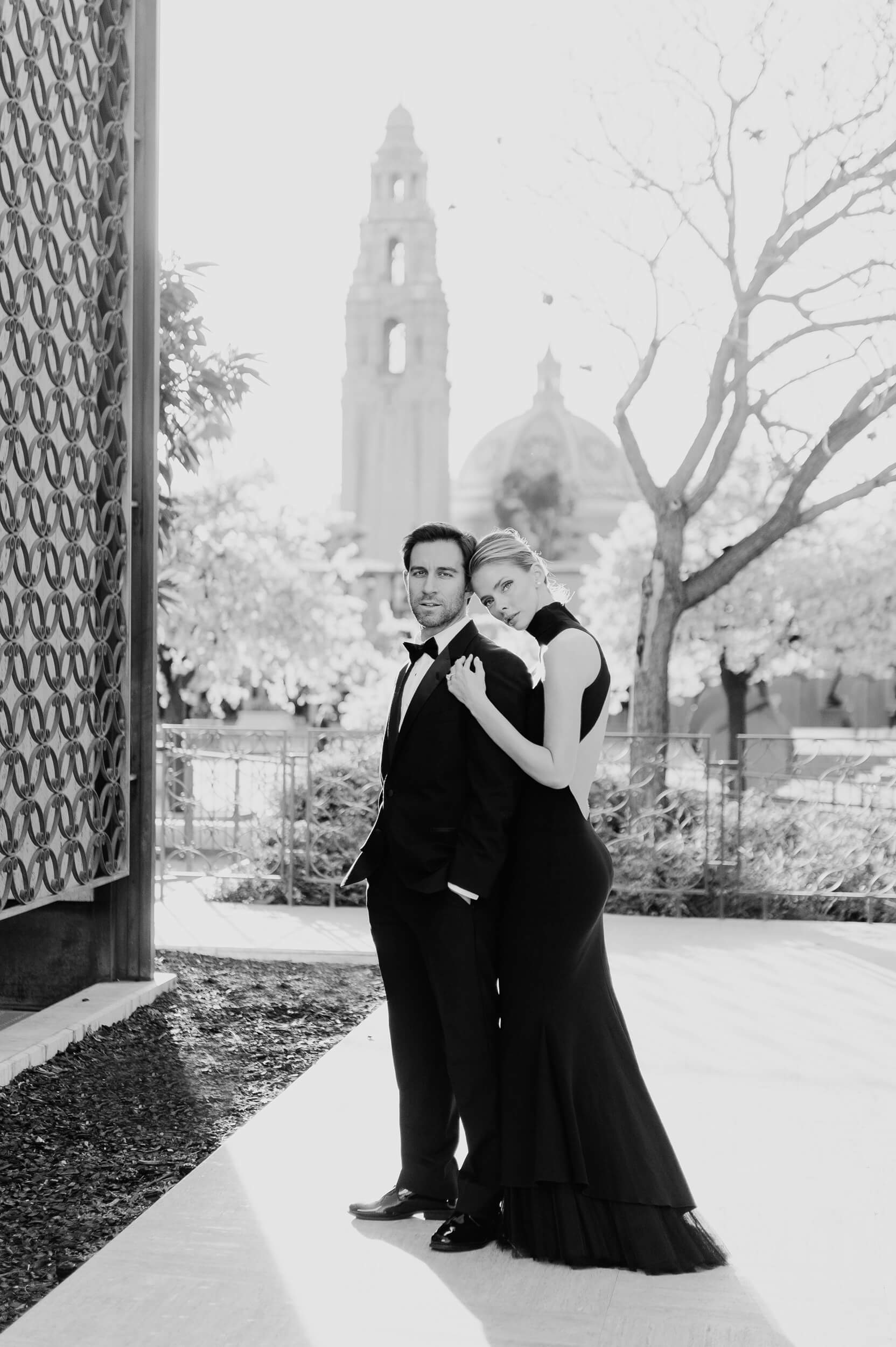 couple pose near mingei museum with california tower in background balboa park