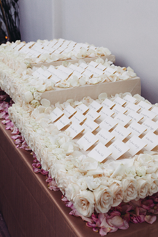 escort cards on bed of white and purple roses bacara wedding