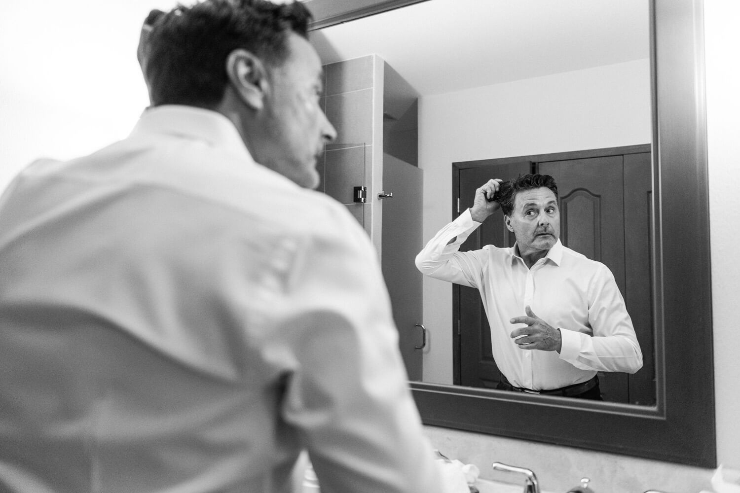 groom fixes hair mirror before wedding