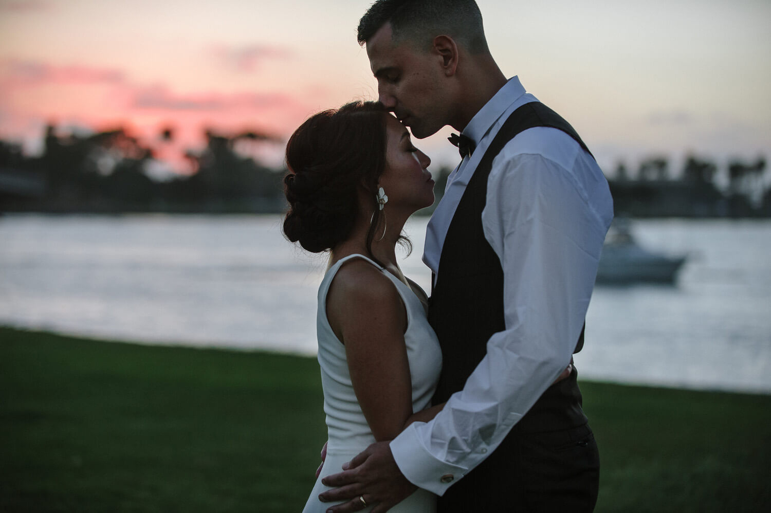 bride and groom kiss at sunset on mission bay