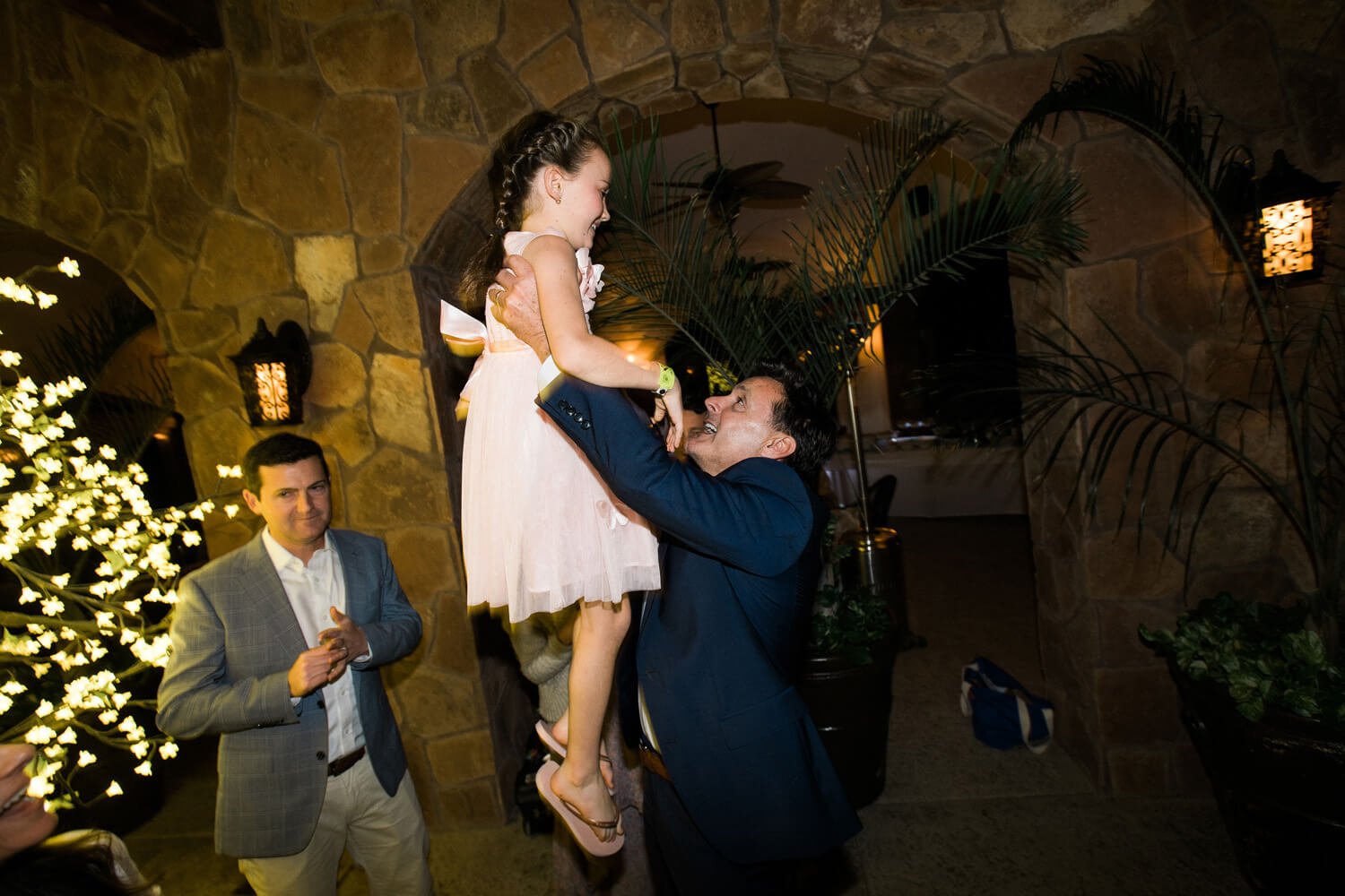 groom lifts flower girl in air dancing wedding reception