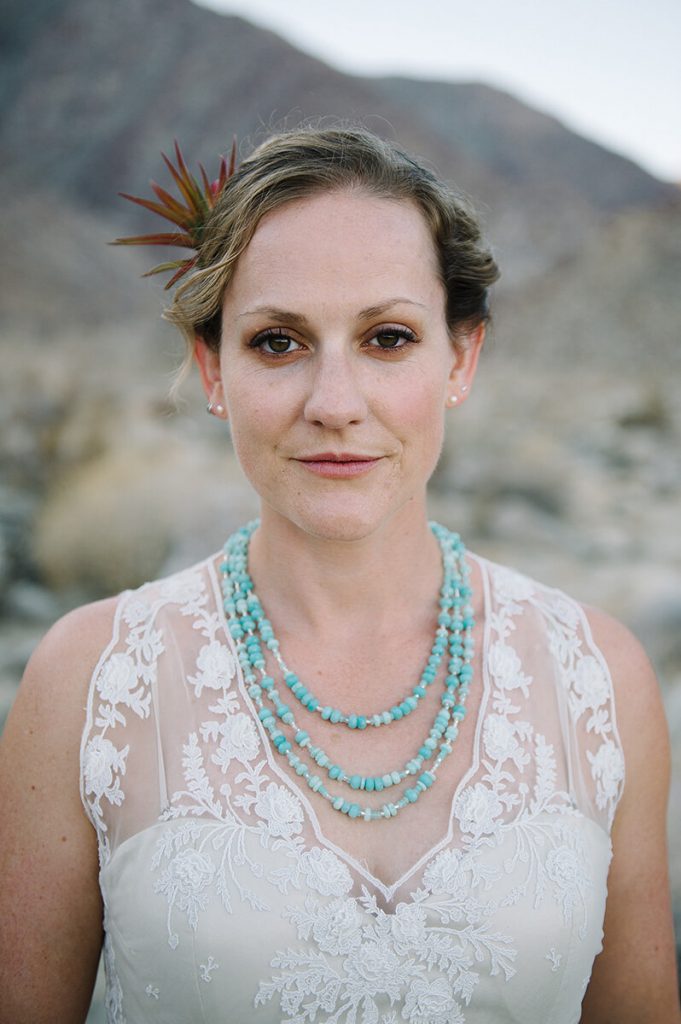 bride wears feather headpiece and turquoise necklace for desert wedding ceremony