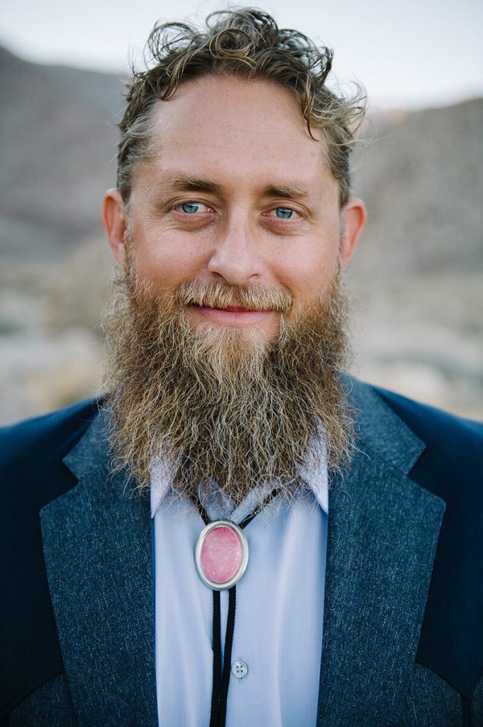 groom with long beard and bolo tie wearing blue suit poses after borrego springs wedding