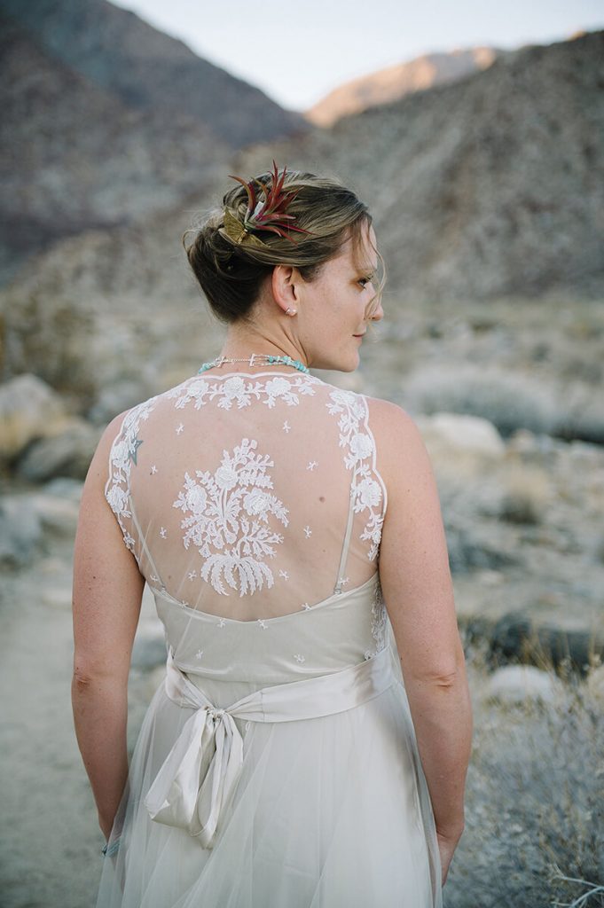 bride shows lace back of wedding dress after desert wedding ceremony