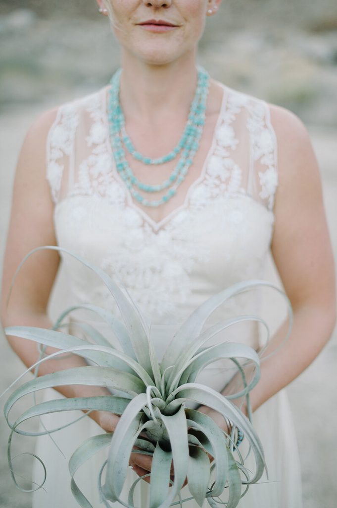 bride holds bouquet made of succulents during desert wedding ceremony
