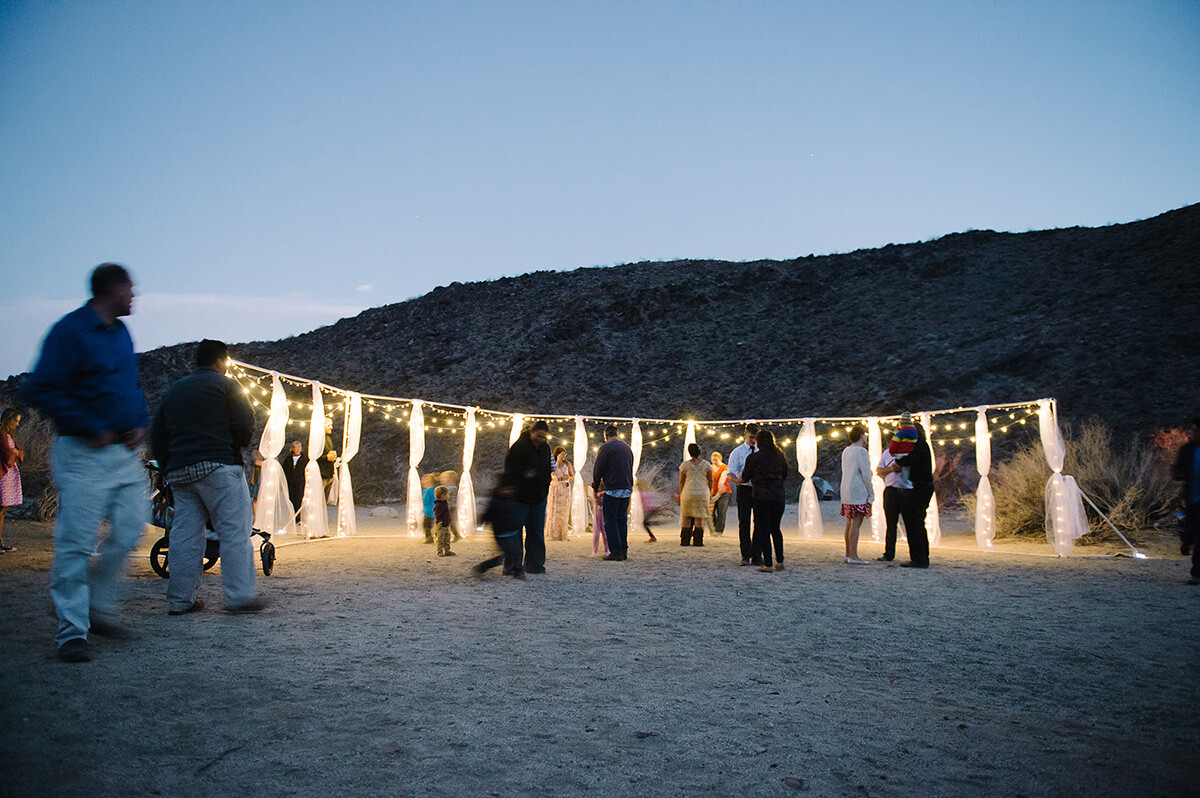 poles with white draping and market lights illuminate desert wedding reception in anza borrego state park