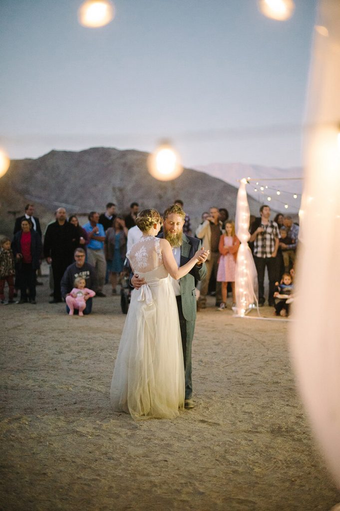 bride and groom do their first dance at dusk under market lights during desert wedding reception in anza borrego state park