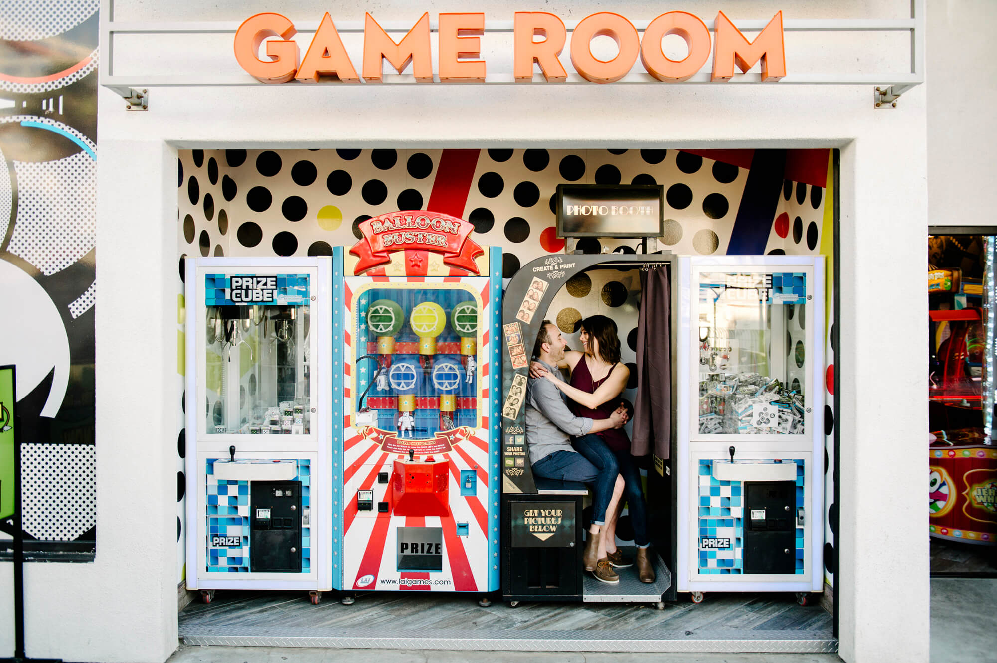 couple pose in game room on midway at belmont park for mission beach engagement photo