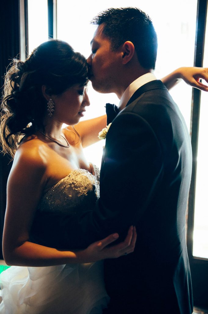 groom kisses brides head inside hotel del coronado