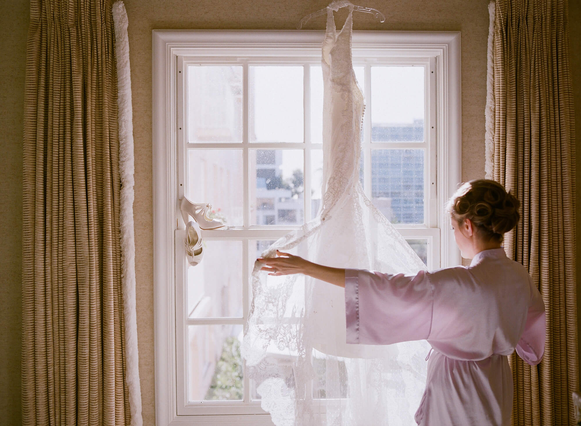 bride touches gown at la valencia hotel window