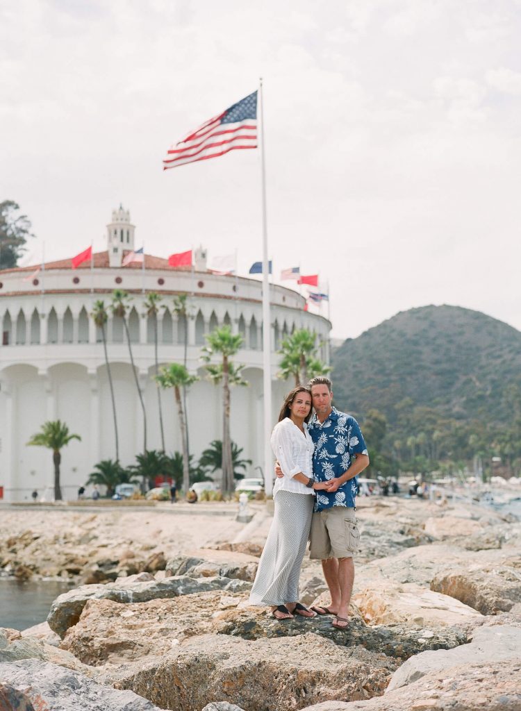 couple posing on jetty in front of avalon casino catalina island