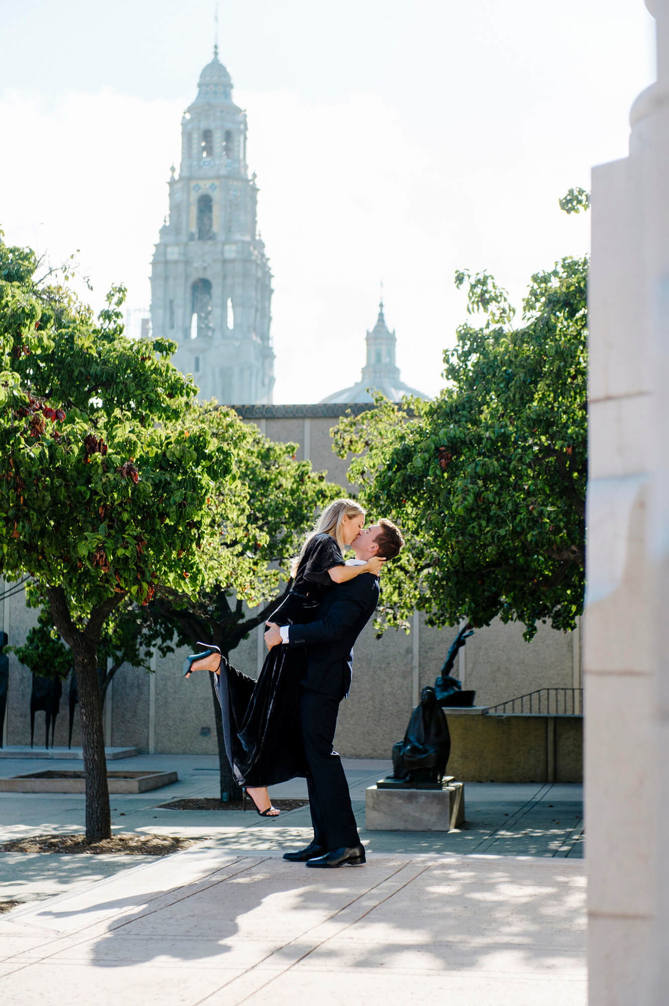 man lifts fiancee in air balboa park engagement