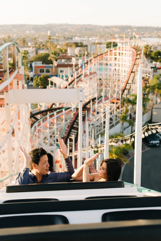 couple giving high fives at top of roller coaster belmont park engagement shoot