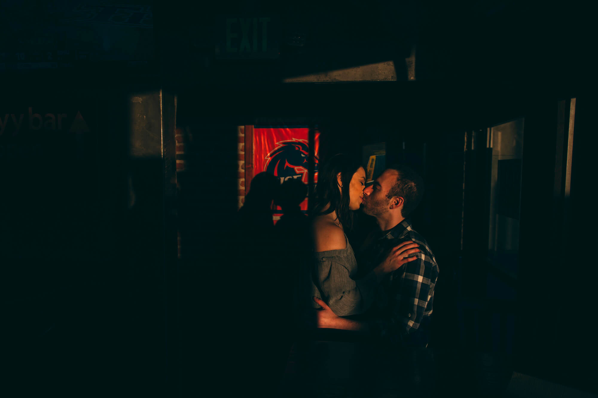 couple kiss at sunset in bar with boise state flag in background