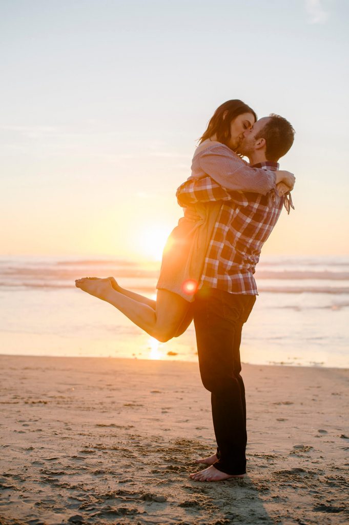 man lifts fiancee off feet sand mission beach