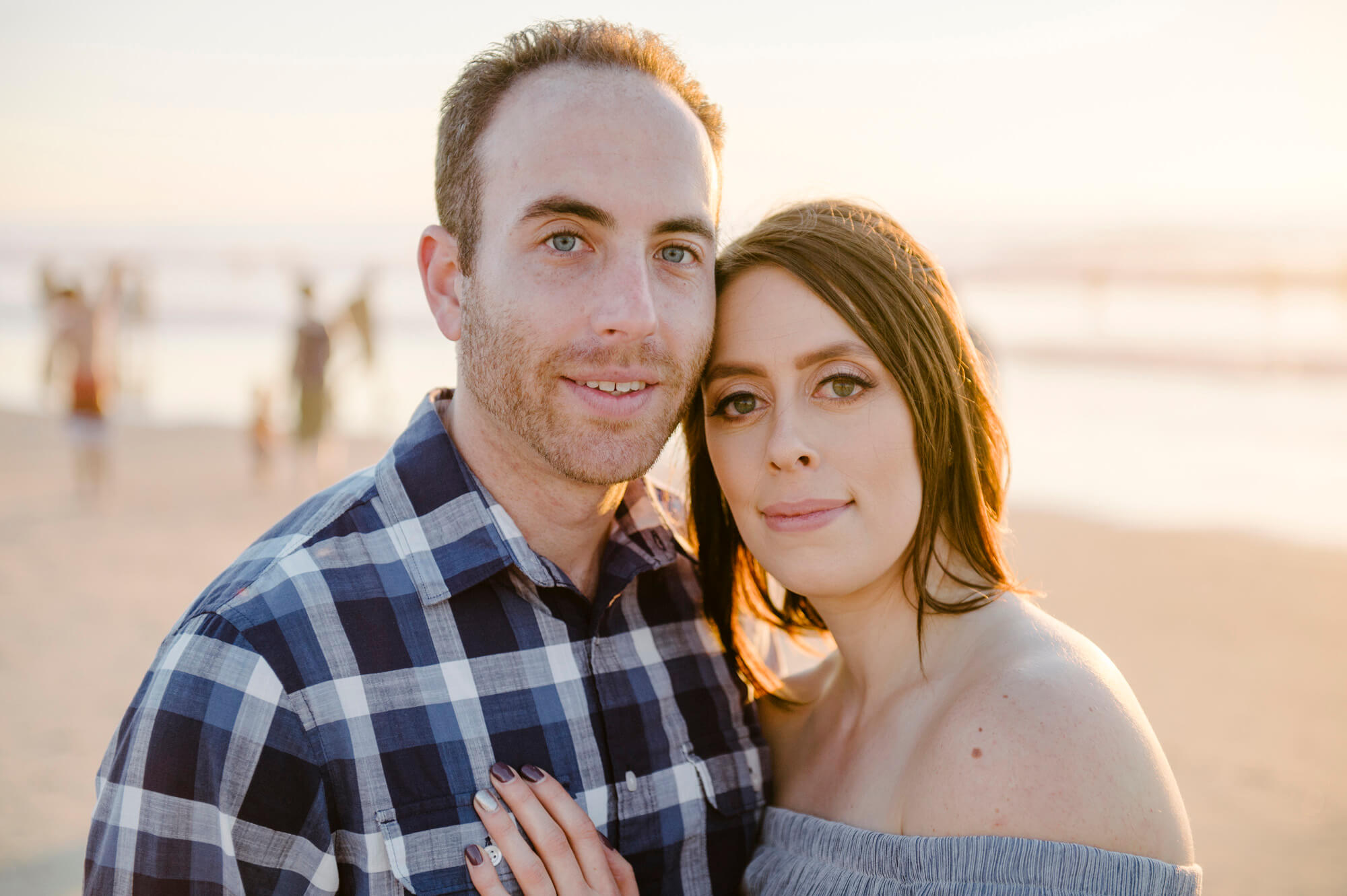 couple pose on mission beach for portrait at sunset