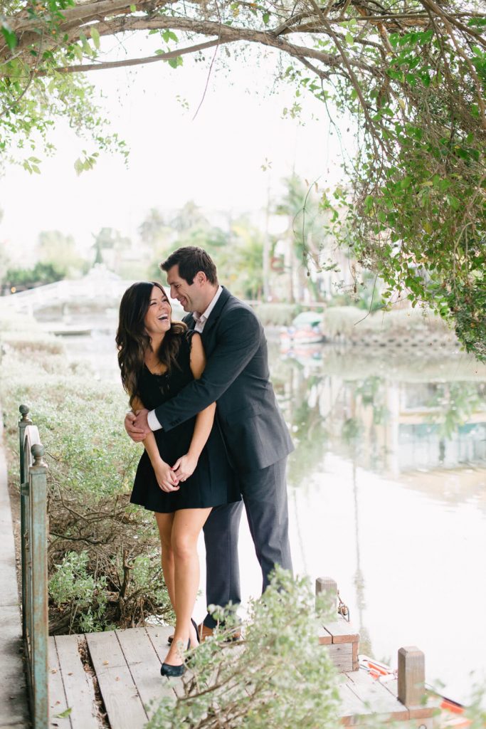 man embraces fiancee laughing venice canals engagement photo