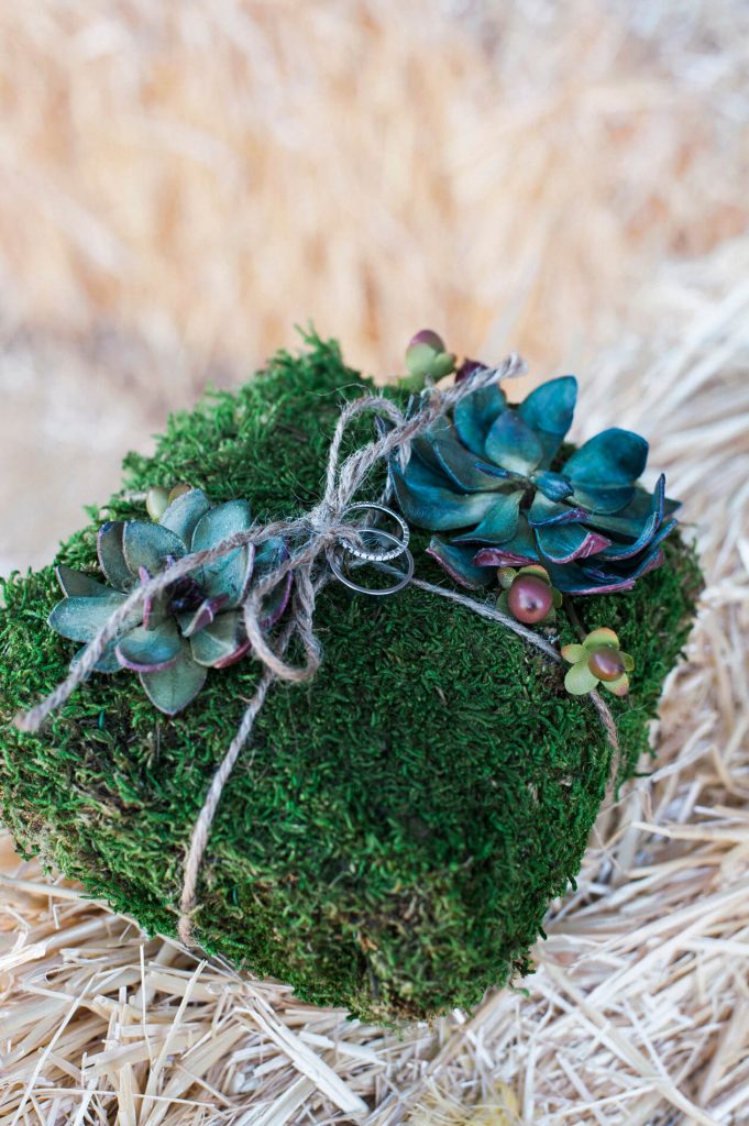 moss wrapped in twine and covered in succulents holding wedding ring