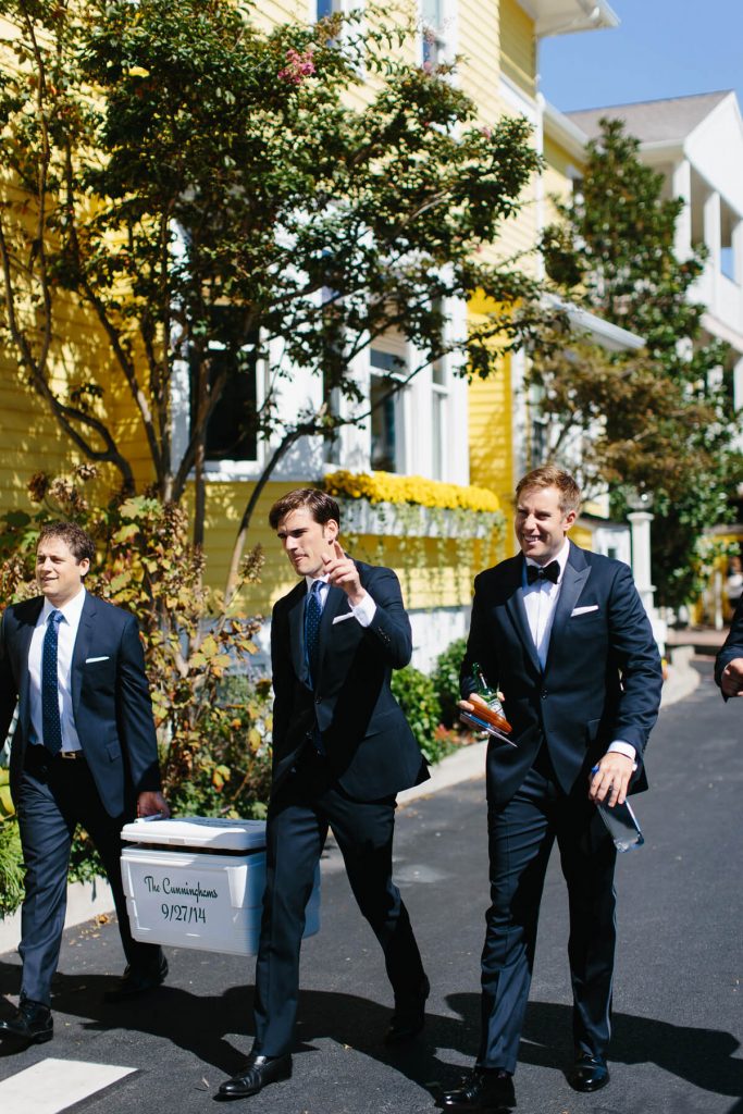 groom and groomsmen carry ice chest