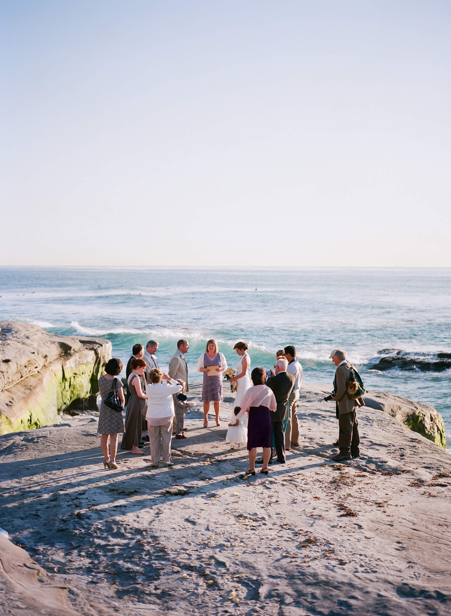 bride and groom and guests on rocks a windansea beach intimate wedding