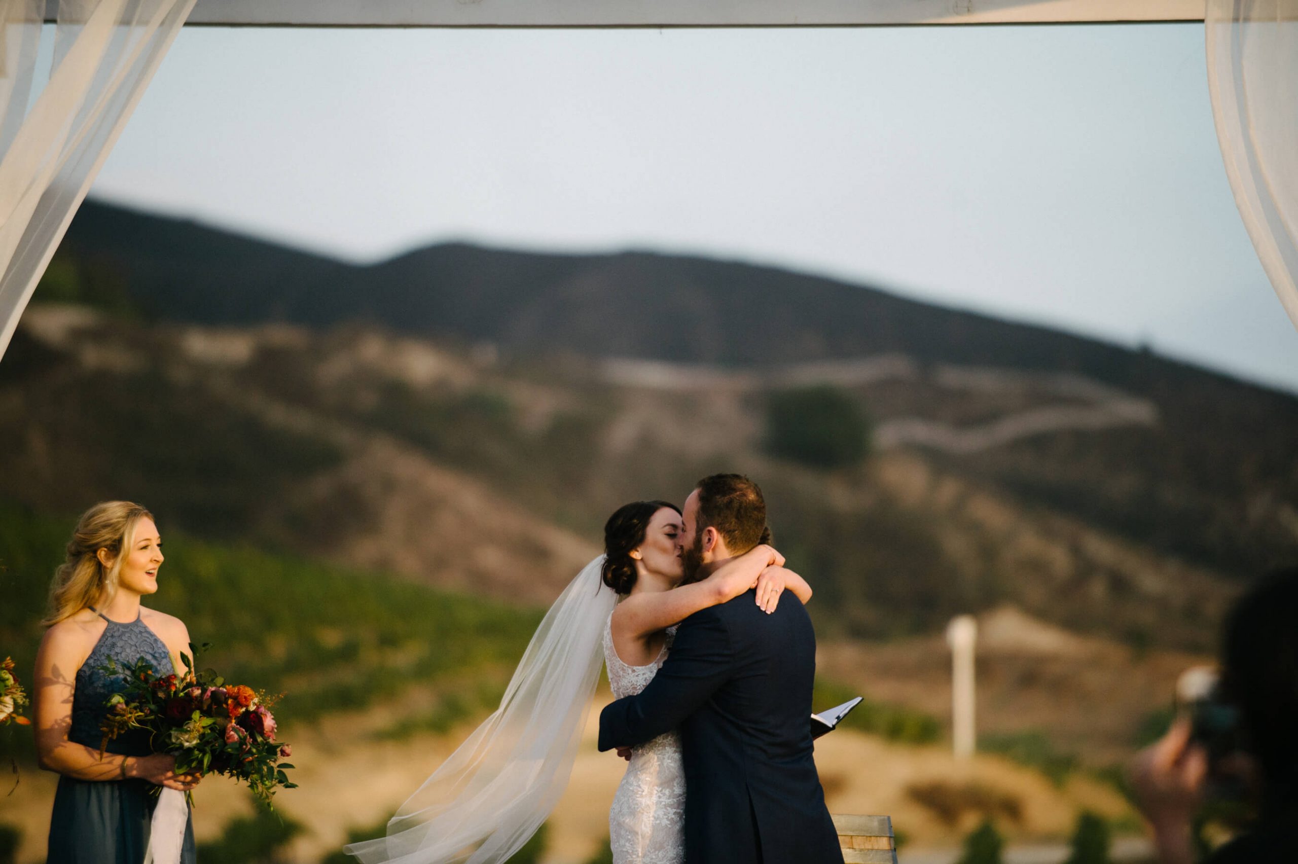 bride groom kiss with mountains and vineyards in background leoness cellars wedding