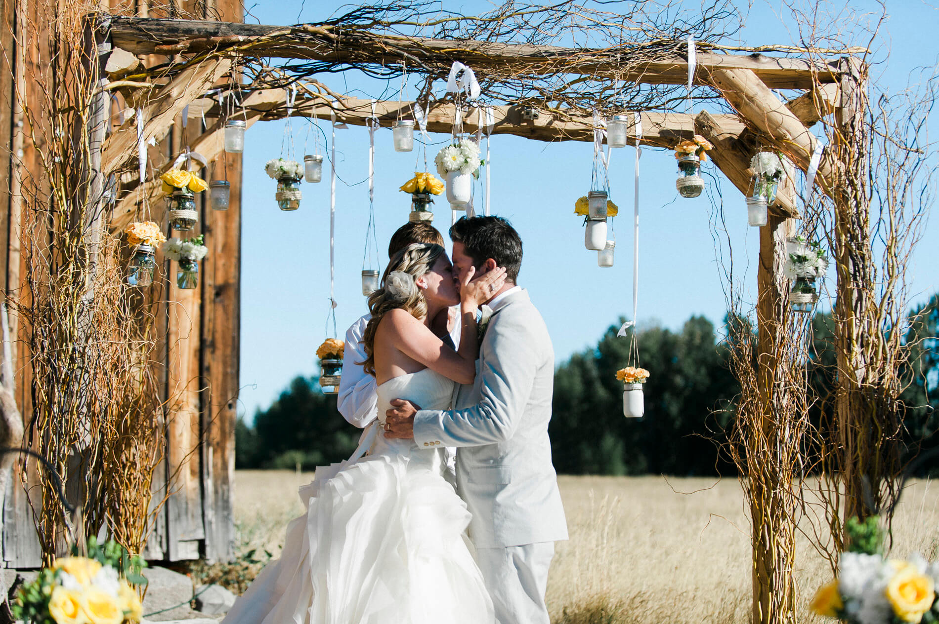 bride and groom kissing under arch lake almanor destination wedding at rustic barn