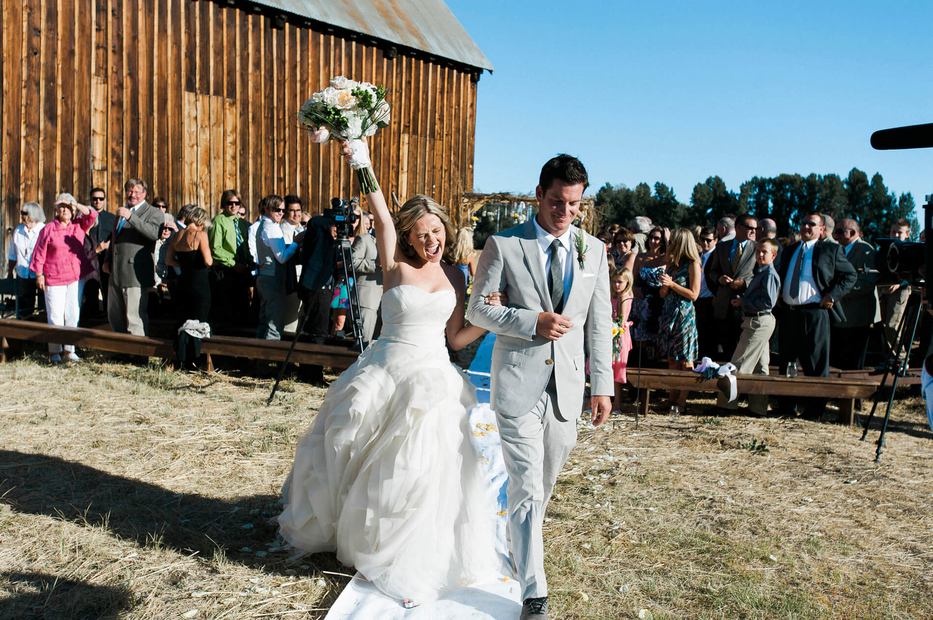 bride raises hand and screams with joy walking with groom lake almanor destination wedding