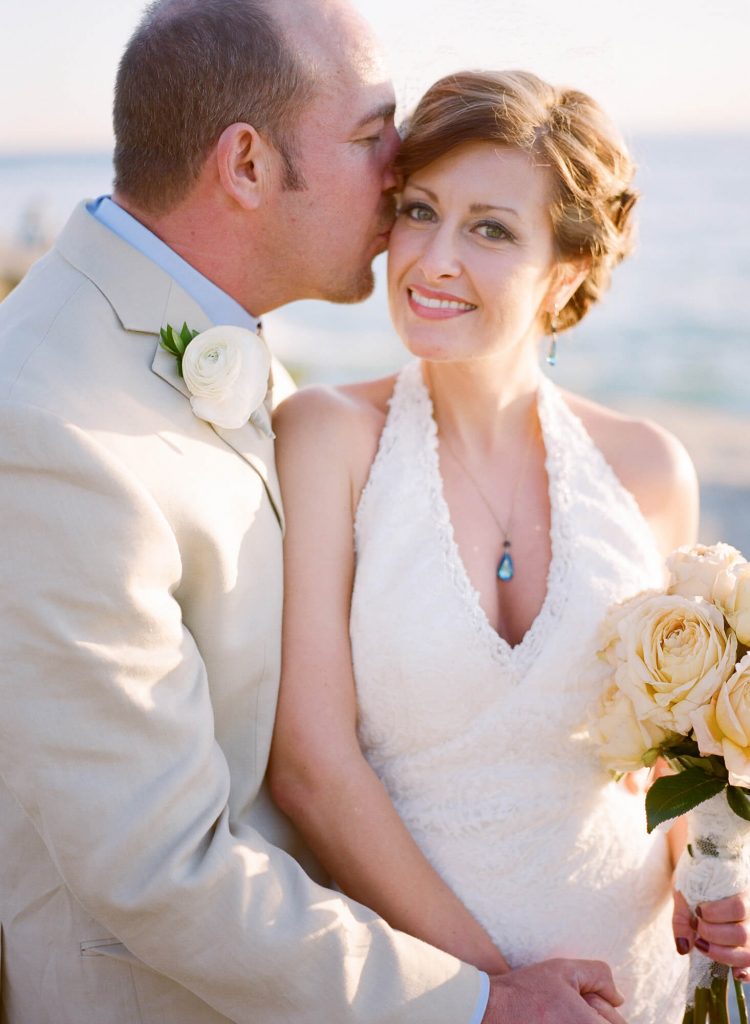 bride and groom embrace beach