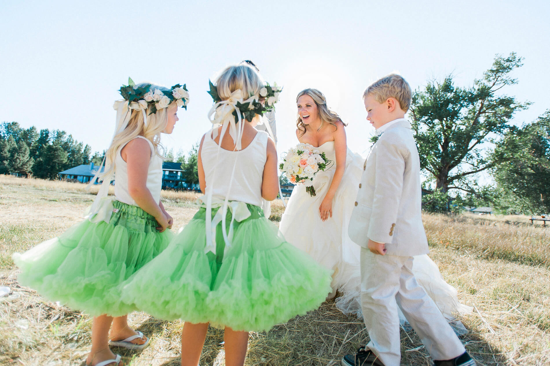 bride and groom surrounded by ring bearer and flower girls after lake almanor destination wedding at rustic barn